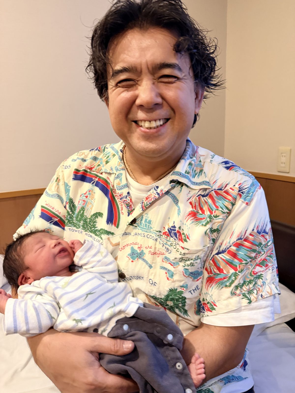 生まれたばかりの孫を抱いて笑う岩上巧