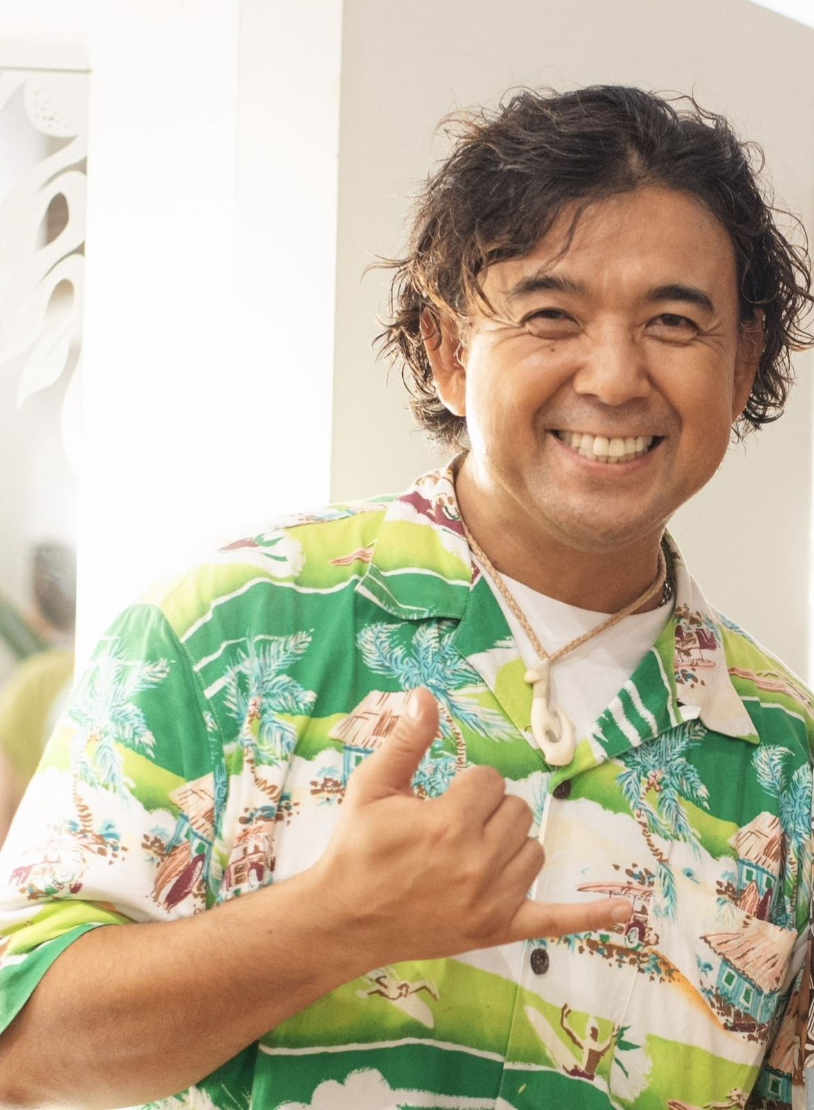 アロハシャツでシャカサインをして笑う岩上巧